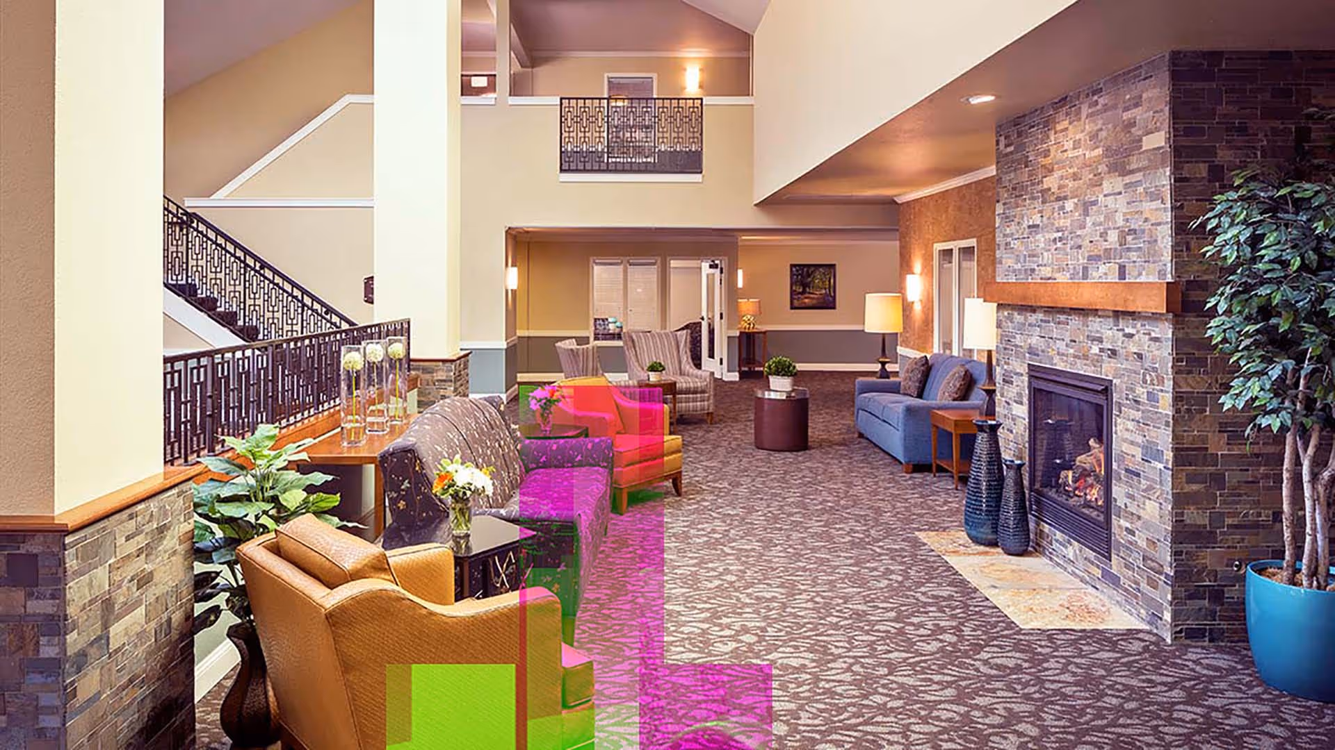 Spacious lounge-style lobby with sofas, armchairs, a stone fireplace, and decorative plants under a high ceiling.