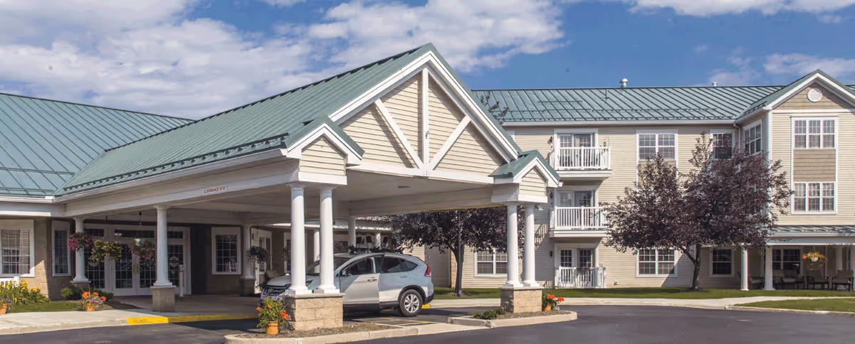 Exterior view of Quail Summit senior living facility with covered entrance and parked car.