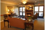 Comfortable lounge area with sofas and chairs arranged around a fireplace and coffee table near glass entry doors.