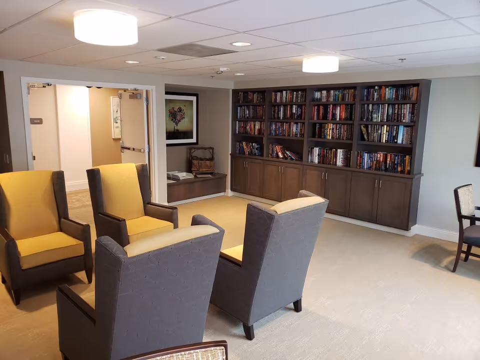 Lounge area with upholstered armchairs arranged facing a large built-in bookshelf wall.