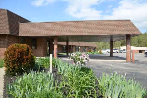 Brick senior living facility with a covered entrance and landscaped front garden.
