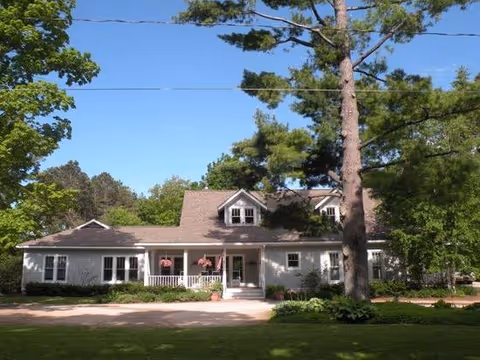 Exterior of a single-story care facility with a porch and surrounding trees.