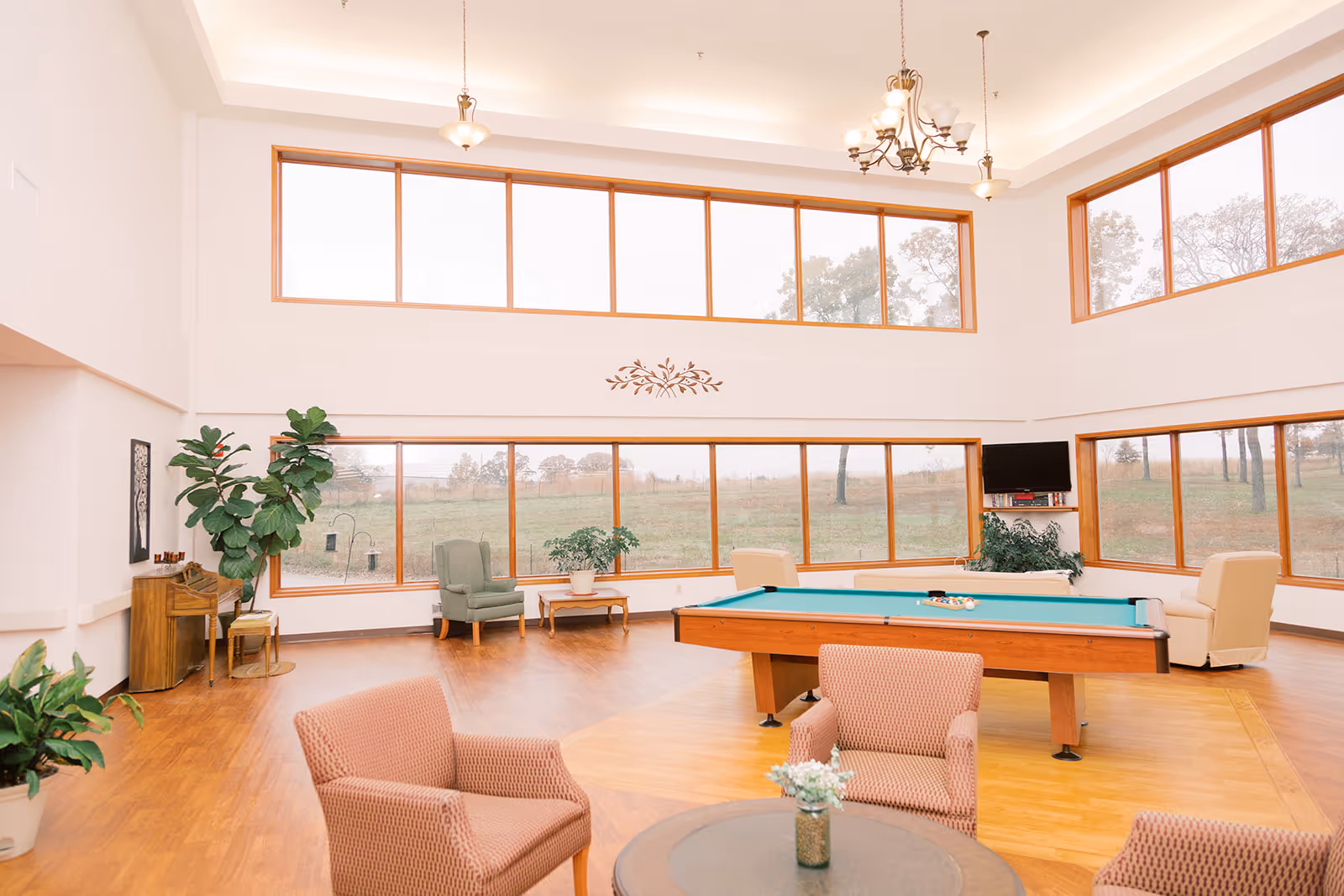 Bright, spacious lounge with large windows, seating areas, plants and a pool table.