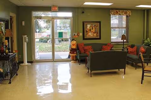 Cozy lobby lounge with green walls, red cushions, and glass doors at Crockett County Nursing Home.