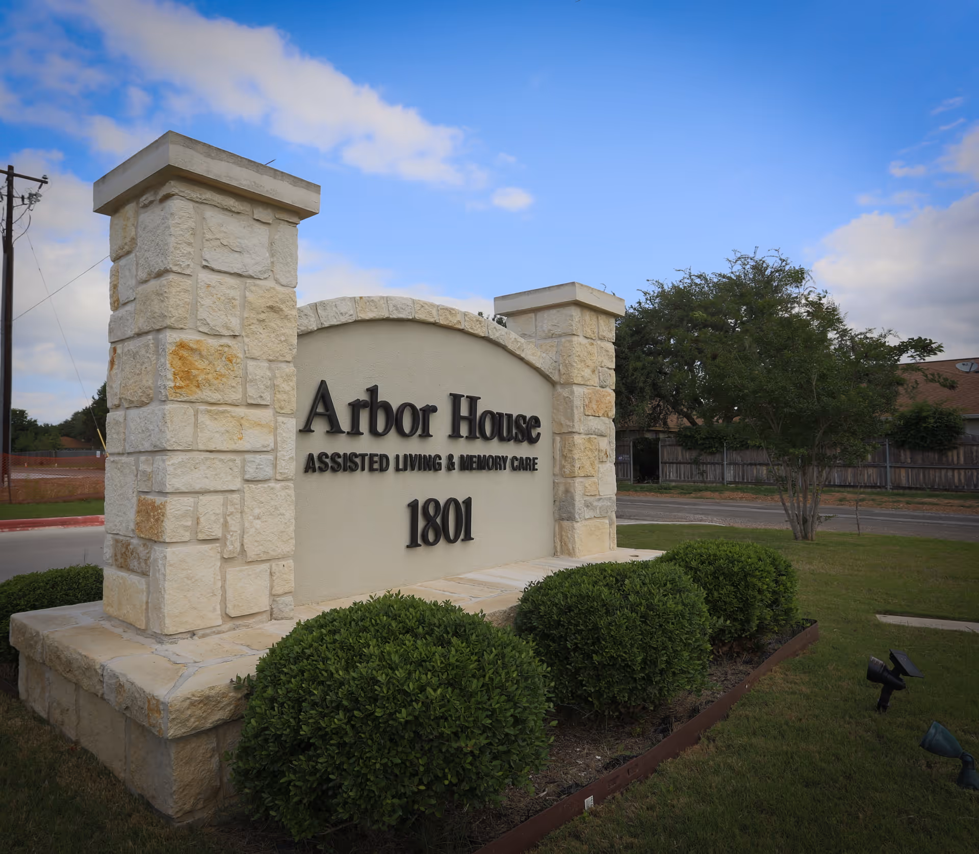 Sign for Arbor House Assisted Living and Memory Care with landscaping in view.