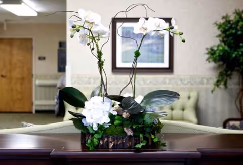 Floral arrangement on a dark reception desk inside a senior living facility lobby.