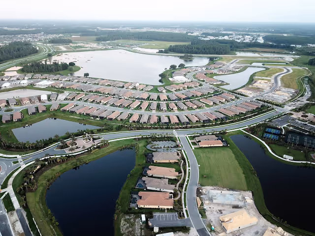 Aerial view of a residential community with rows of houses, curved roads and multiple ponds and lakes.