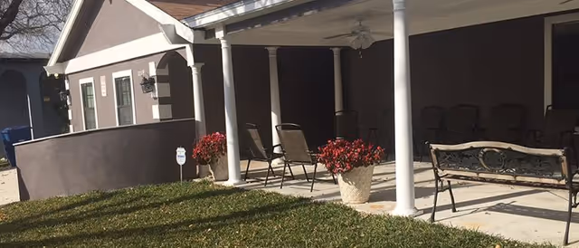Front porch of a senior living facility with seating and potted plants.