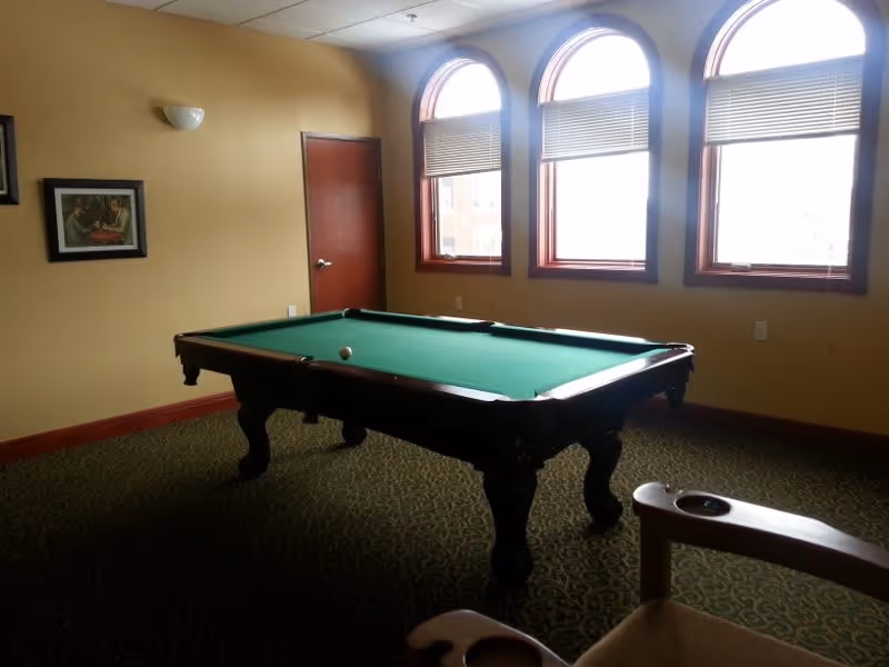 Game room interior featuring a pool table under three arched windows.
