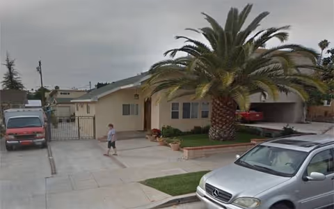 Daly Care facility exterior with a palm tree, parked cars, and a person walking.