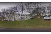Exterior view of New Haven Center for Nursing and Rehabilitation building on a grassy, tree-lined lot.