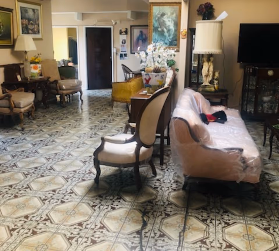 Decorative senior living lounge with a patterned tiled floor and a plastic-wrapped couch.