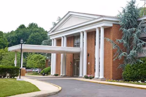 Front exterior of Abingdon Care and Rehabilitation Center with brick facade, columns, and a covered entrance.
