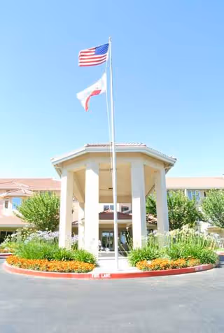 Flagpole and entrance canopy at the Quail Lodge retirement community with circular landscaping.