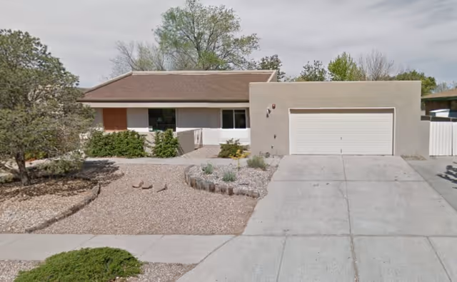 Single-story stucco house with a two-car garage and a gravel front yard with desert landscaping.