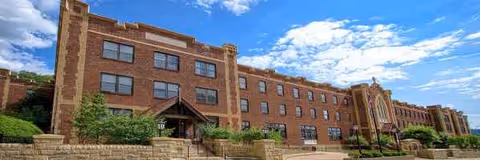A brick senior living facility building with multiple windows under a blue sky.