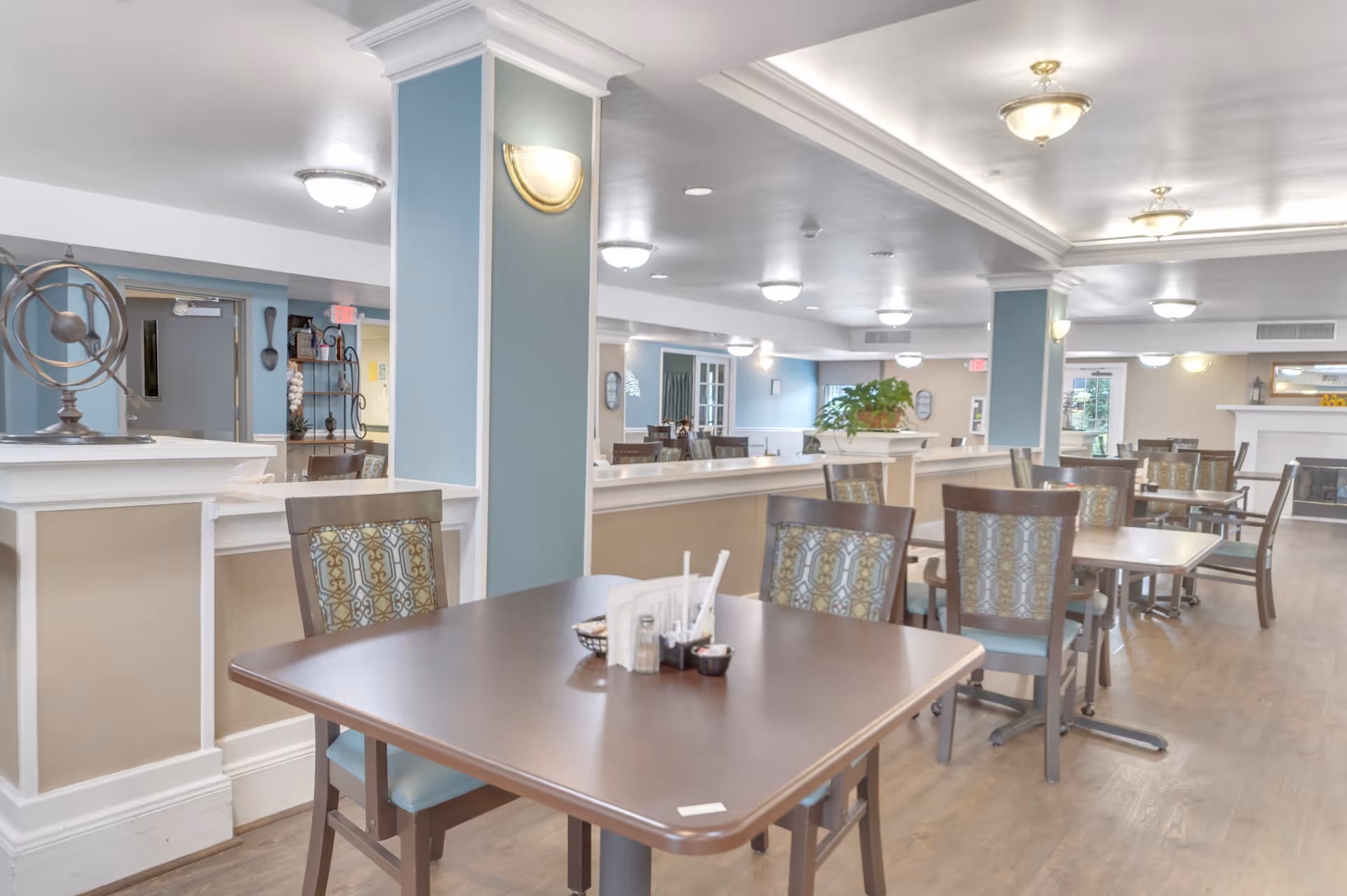 Bright communal dining room with multiple tables and chairs in a senior living facility.