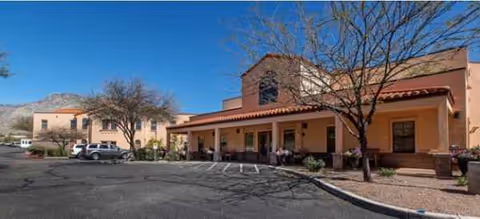 Senior living facility exterior with a covered entrance, parking lot, and desert landscaping.