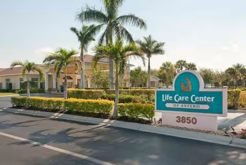 Exterior view of Life Care Center of Estero with a sign and palm trees.