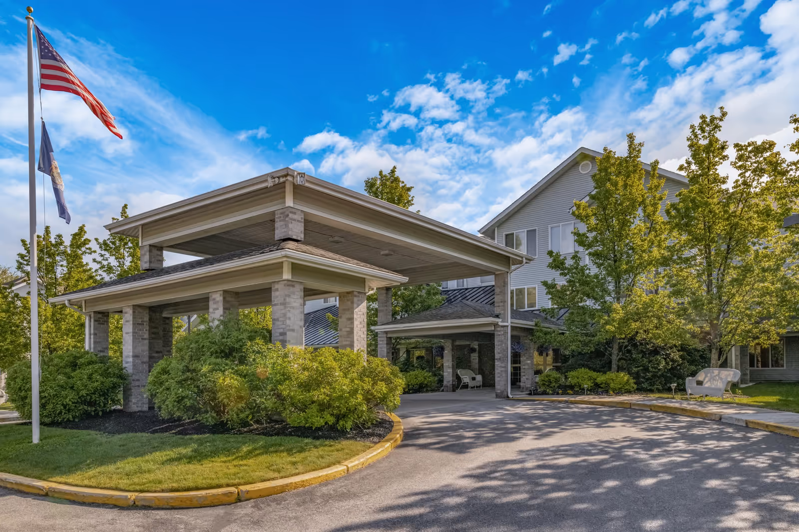 Facade of Holiday Woods at Canco with a covered entrance and landscaped surroundings.