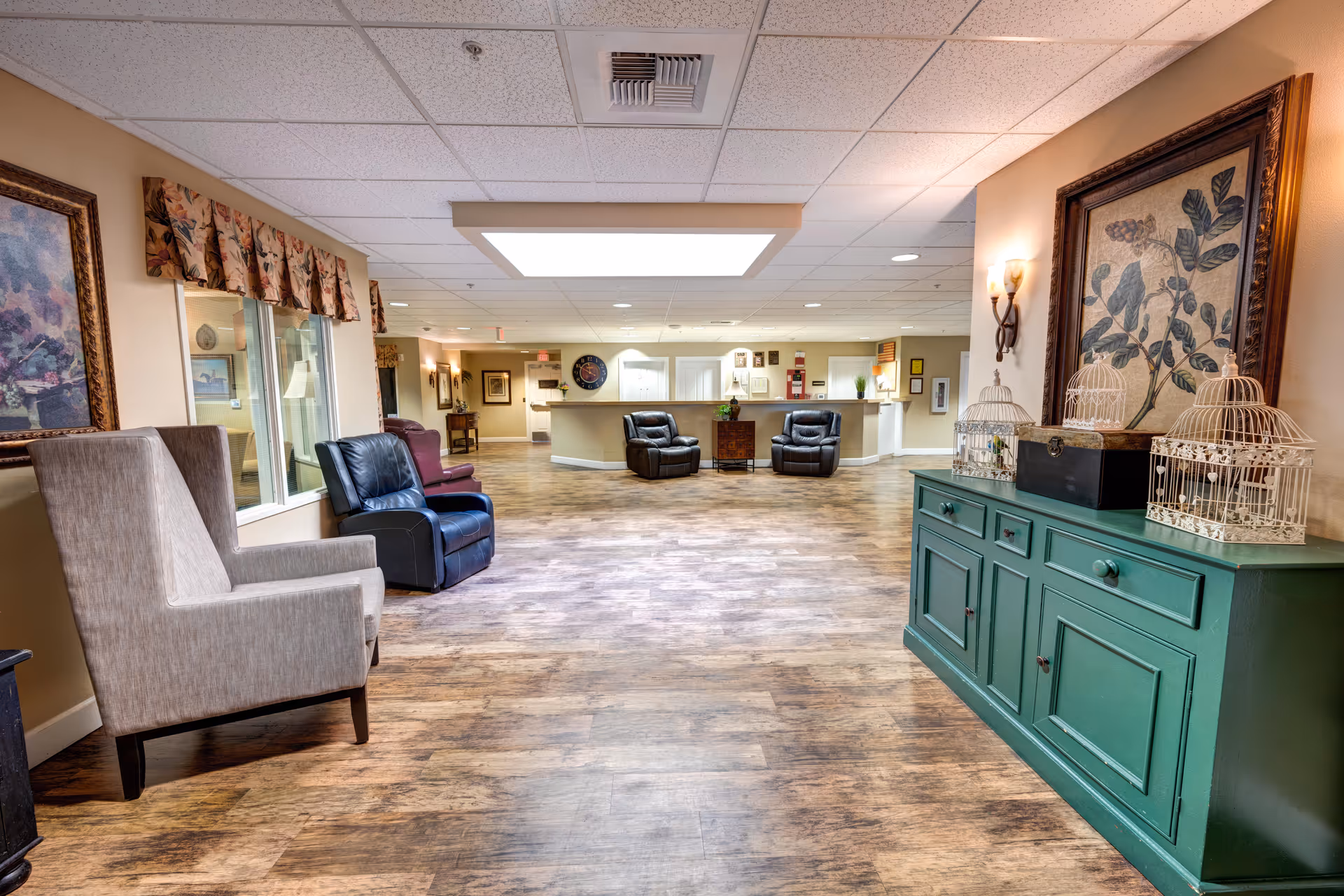 Spacious senior living lobby with seating, a reception desk, and wall art.