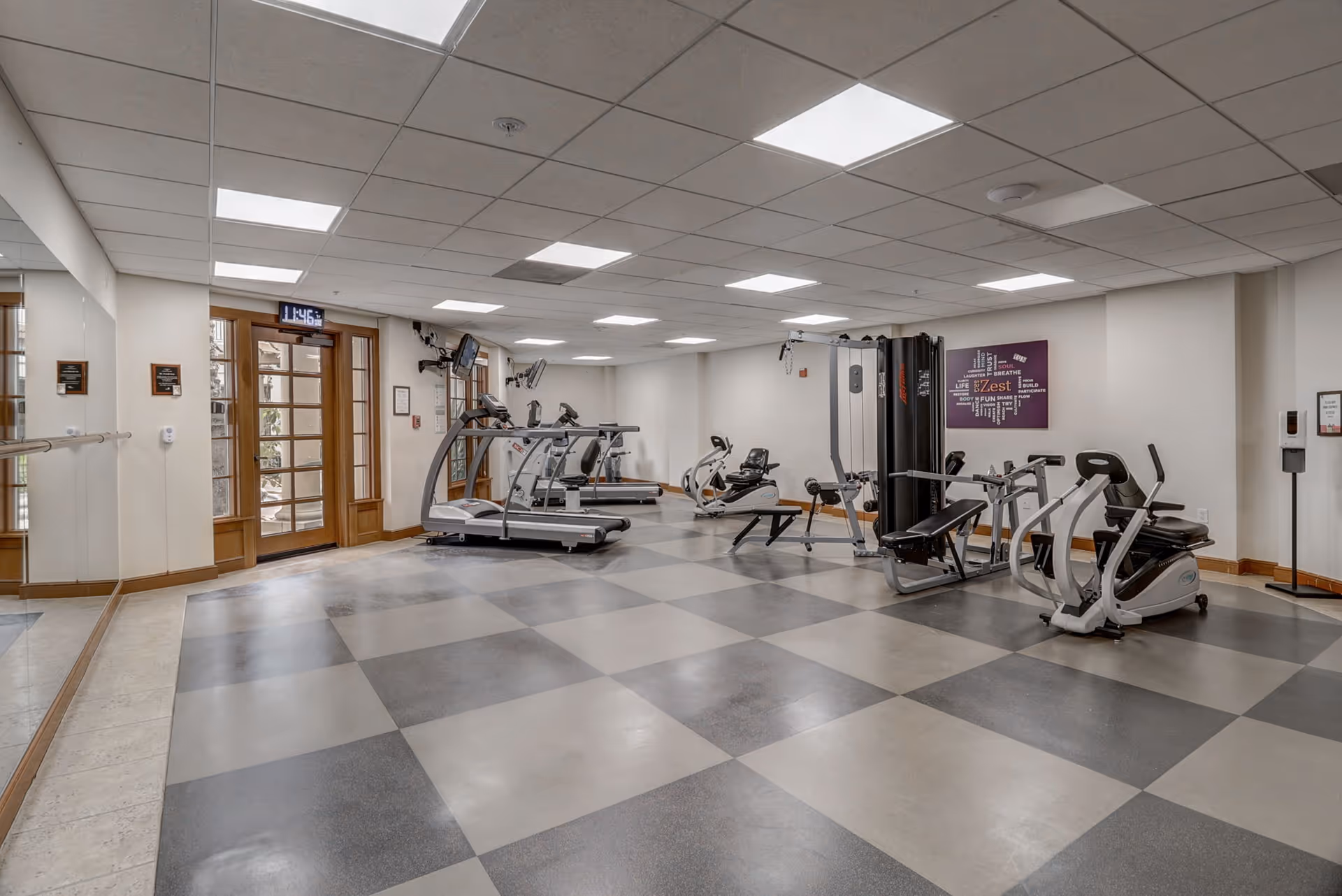 Spacious indoor fitness room with treadmills, stationary bikes, weight machines and a mirrored wall.