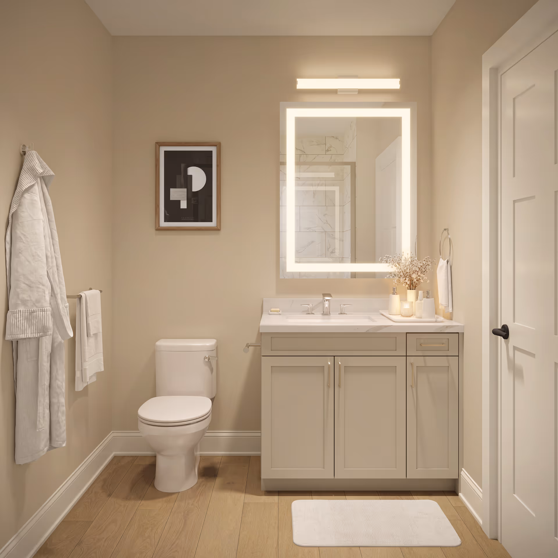 A modern bathroom with beige walls and wooden floor. It features a white toilet, a vanity with a white countertop and sink, a large illuminated square mirror above the sink, and a white door on the right. There are white towels hanging on a towel rack and a hook, a framed abstract black and white artwork on the wall, and decorative items including a small vase with dried flowers on the vanity.