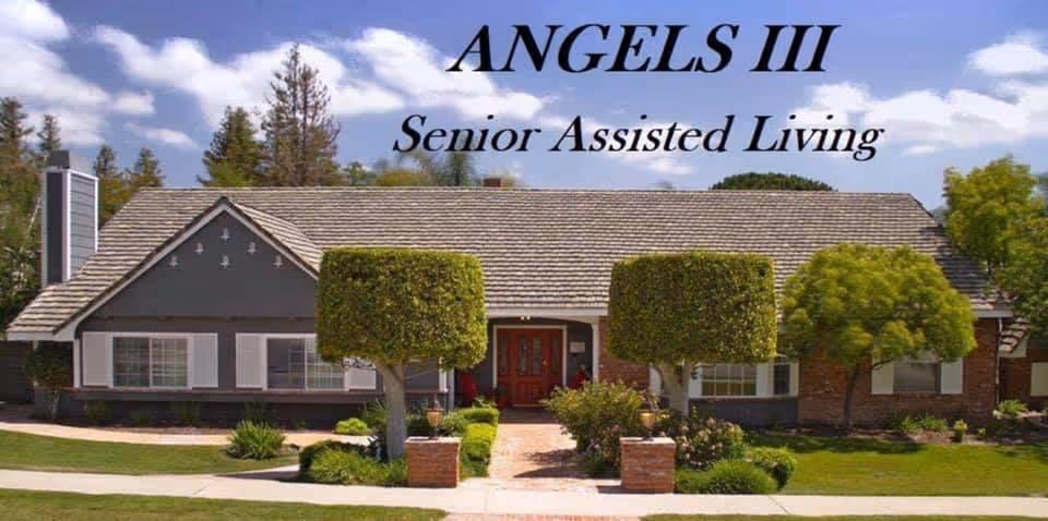 Front exterior view of a single-story senior assisted living facility named Angels III, featuring a well-maintained lawn, trimmed trees, and a pathway leading to a double-door entrance under a tiled roof with a chimney.