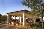 Exterior view of a covered entrance with columns and planters at a senior living facility.