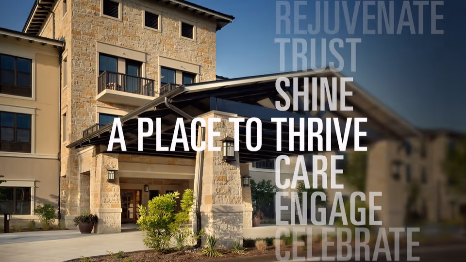 Front entrance of a stone-faced senior living building with a covered porte-cochère and large overlaid promotional text reading "A PLACE TO THRIVE".