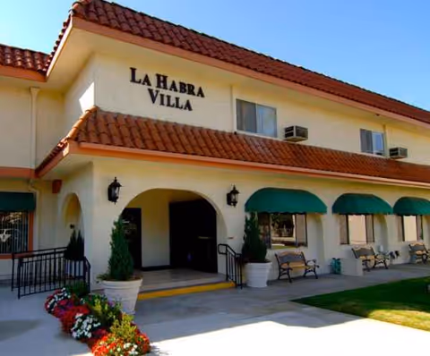 Exterior view of La Habra Villa retirement village with arches, benches, and planters.