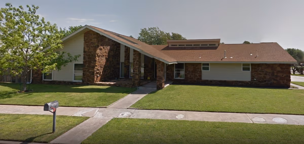 Single-story building with a sloped roof and stone and siding exterior, surrounded by a well-maintained lawn and a sidewalk leading to the entrance. A mailbox with the number 305 is visible in the front yard.