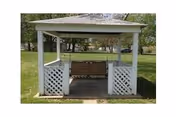 A white wooden gazebo with a bench swing inside, situated on a grassy lawn with trees in the background.