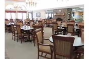 Spacious dining room with round tables, wooden chairs, chandeliers, and a stone fireplace.