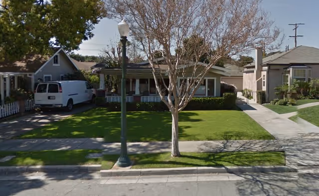 Front view of a single-story senior living home with manicured lawn and white van.