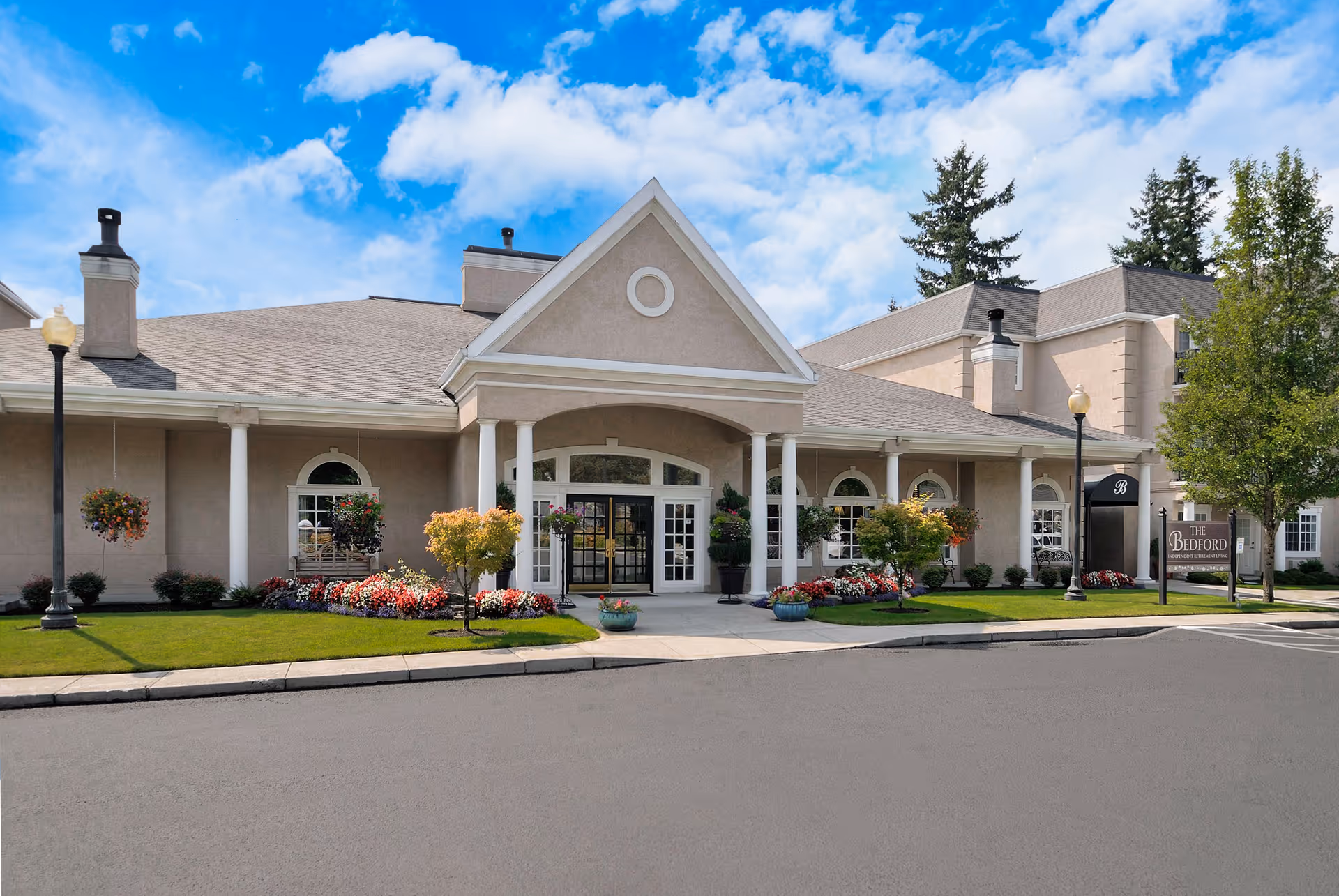 Low-angle view of Truewood by Merrill facility front with columns, landscaping, and a welcoming entrance.