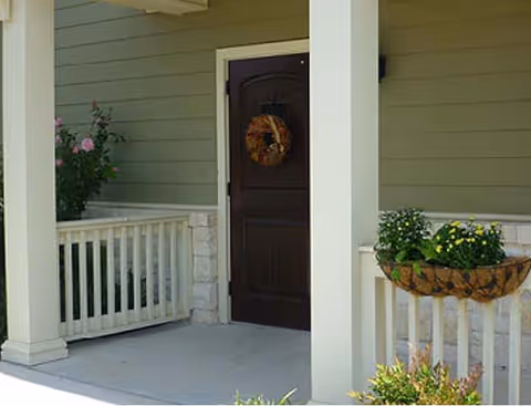 Front entrance of a senior living facility with a dark door, wreath, and planters.