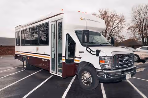 White shuttle bus parked in a lot beside Landmark of Bardstown Rehabilitation and Nursing.