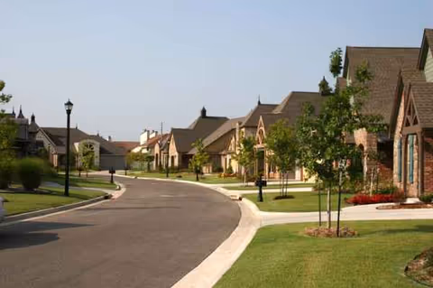 Curved street with townhome-style buildings and manicured lawns at Zarrow Pointe.
