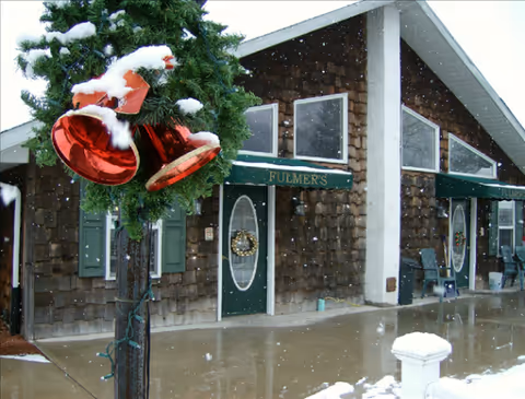Snow-covered Fulmer's Personal Care Home exterior with wooden walls and festive decorations.