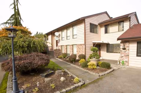 Front exterior of a two-story Gold Autumn AFH senior living facility with landscaped yard.