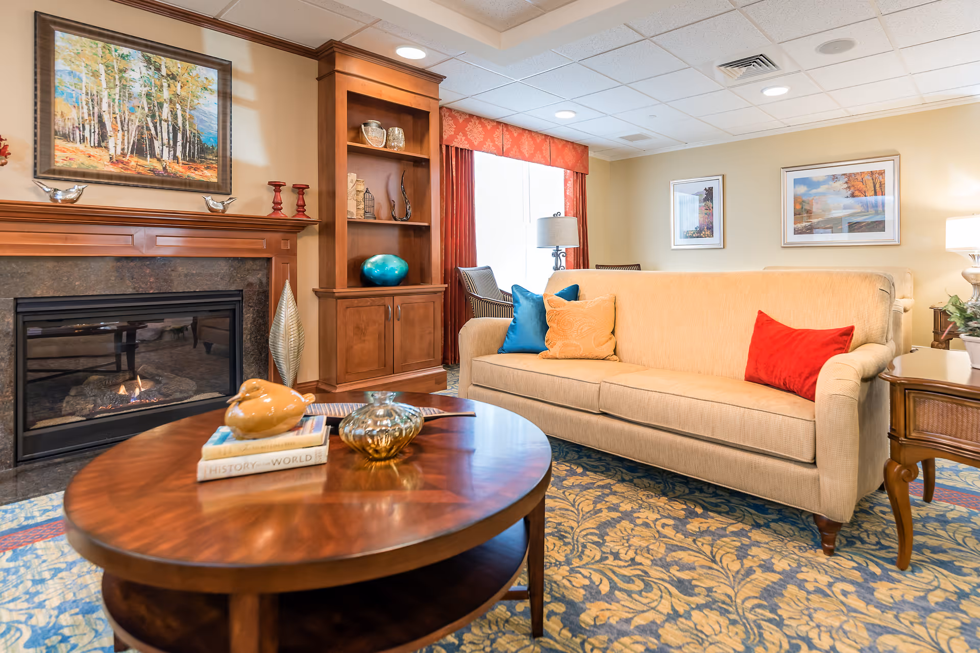 Comfortable living room with a beige sofa, colorful throw pillows, wooden coffee table, built-in shelving, and a fireplace.