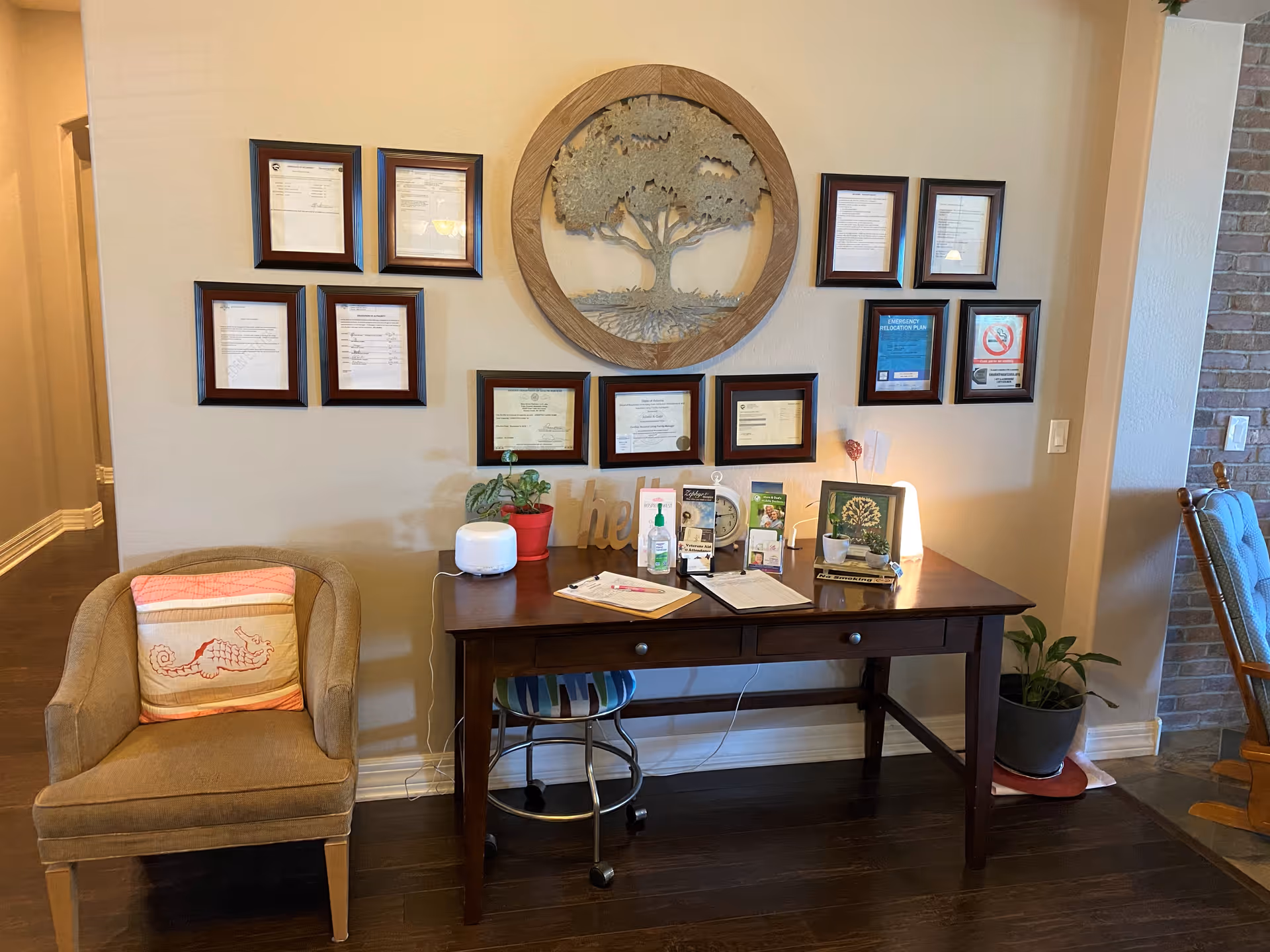 Wood desk against wall with framed certificates and a decorative tree centerpiece in a reception area.