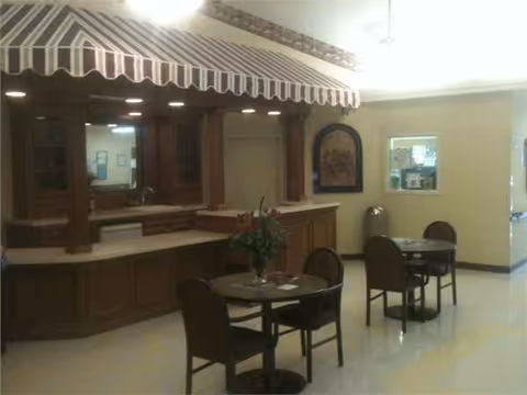 Interior dining area with wooden counter, striped canopy, and small tables with chairs.