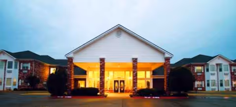 Front entrance of Brookdale North Richland Hills, illuminated canopy and brick exterior at dusk.