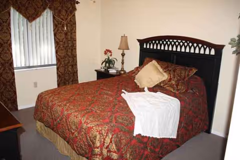 A cozy hotel-style bedroom with a large bed, dark wood headboard, lamps, and curtains.