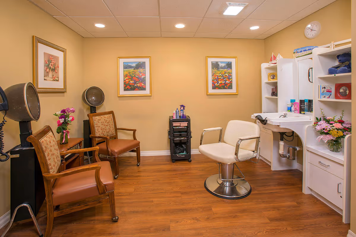 Small hair salon/styling room with chairs, hooded dryers, a styling chair and sink, and floral decor.