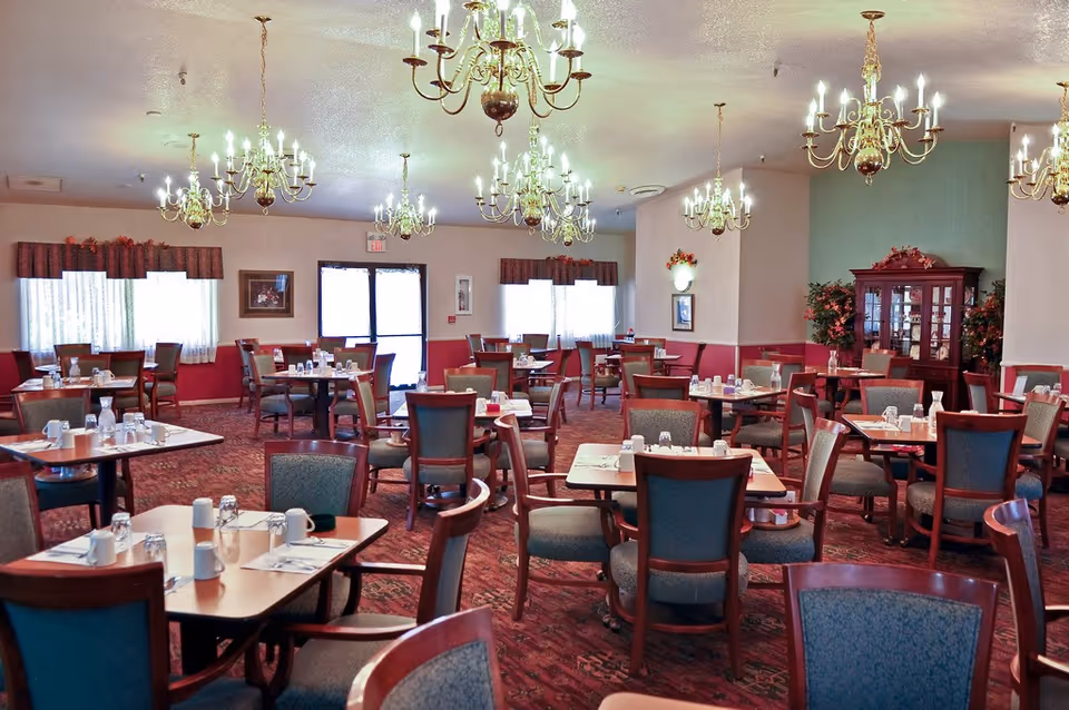 Spacious dining room with multiple set tables, upholstered chairs, and chandeliers.