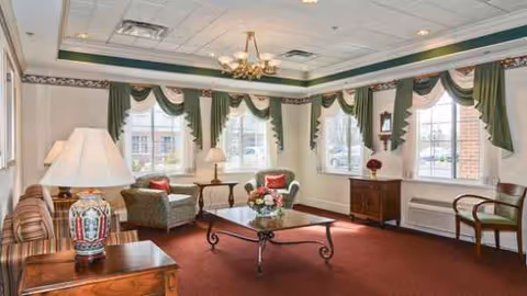 Spacious living room in Northampton Post Acute facility with multiple chairs, sofas, and a coffee table.