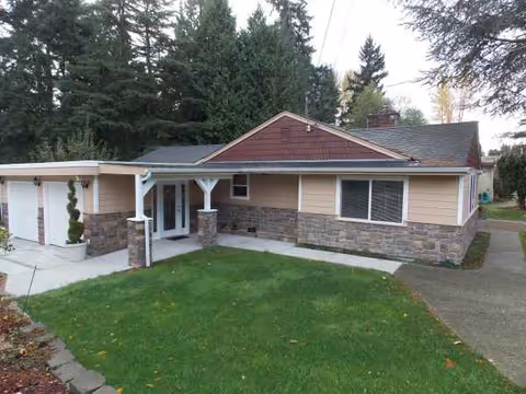 Front exterior of a single-story beige building with stone accents and lawn.